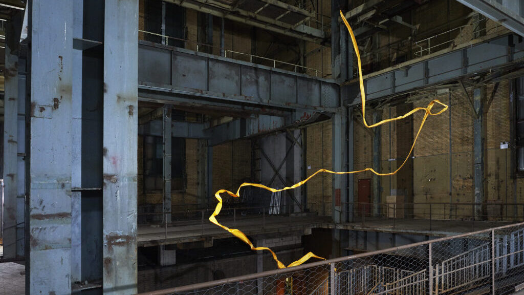 Een gele lint wapperd door een industrieel pand. Onderdeel van het kunstwerk Hula van Zoro Feigl.