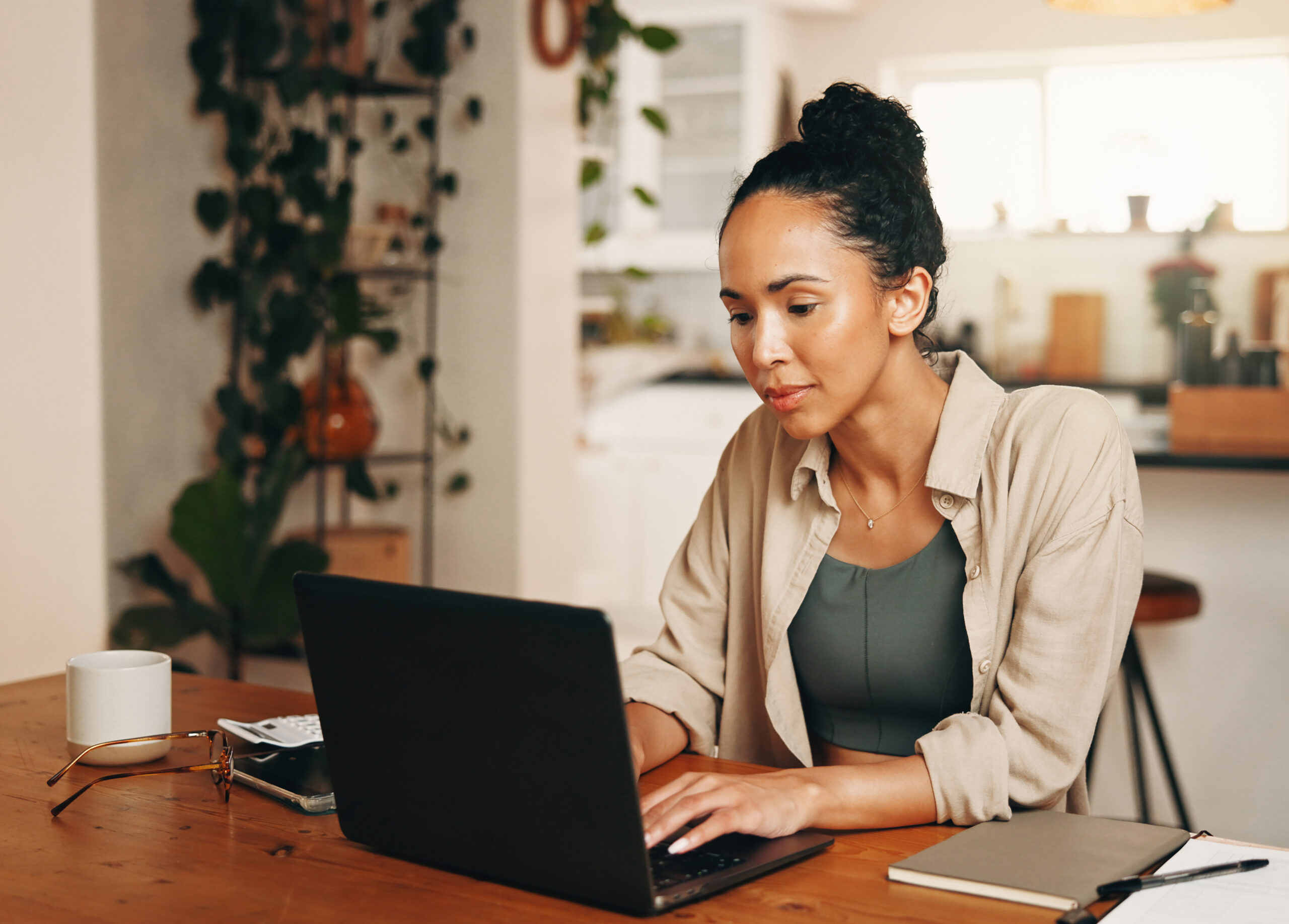 vrouw achter laptop aan keukentafel. 